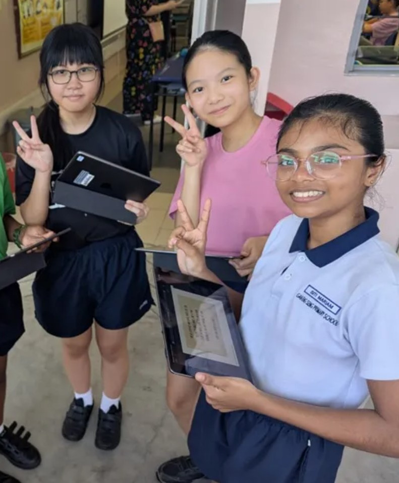 A group of 3 students poses together with their tablets, highlighting teamwork and technology in education